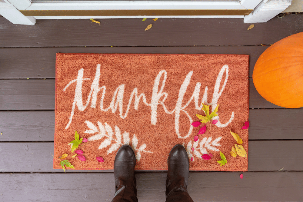 A person standing on a porch with an important reminder of gratitude - a doormat that says thankful.