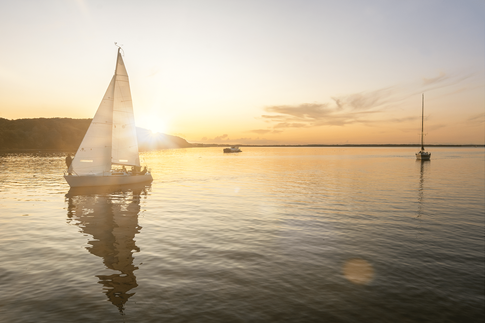 Description: A sailboat gliding on the water, bathed in the warm hues of a breathtaking sunset.