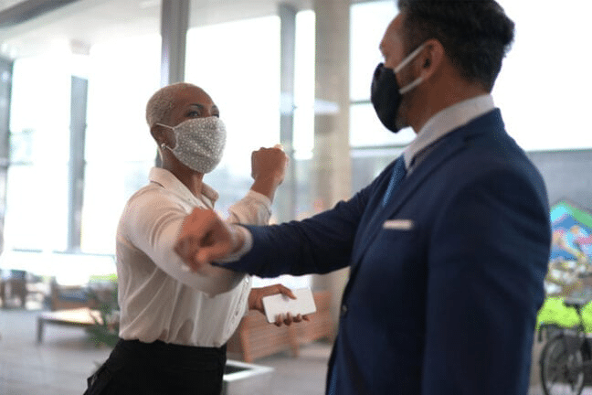 A woman in a business suit and a man in a face mask exhibit EV readiness on the EV campus.
