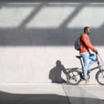 A man is biking in front of a wall.