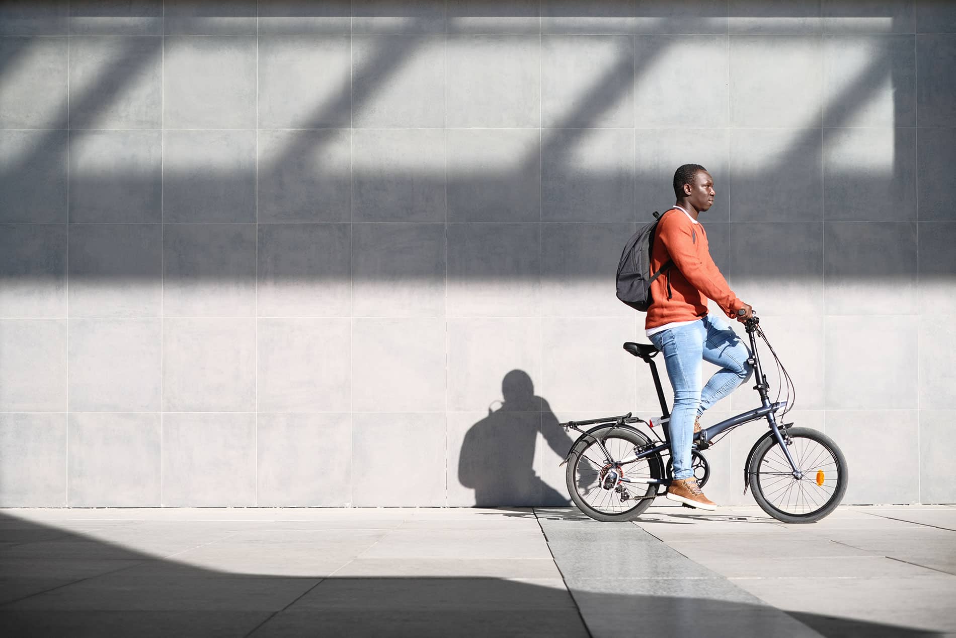 A man is biking in front of a wall.