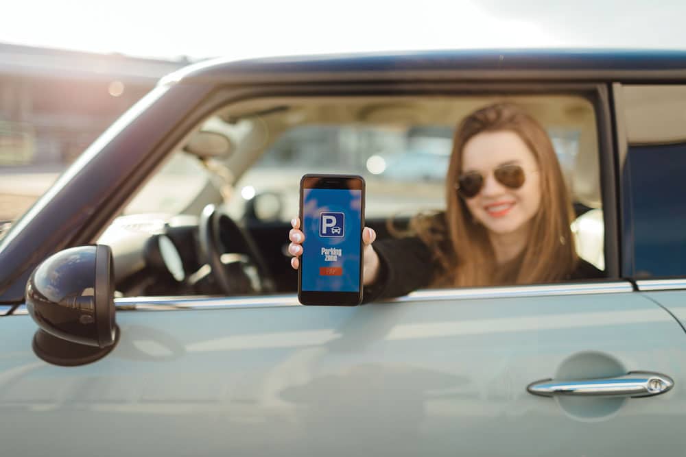 Woman in car holding phone to show mobile parking app