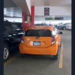 Compact orange car in a tight parking spot