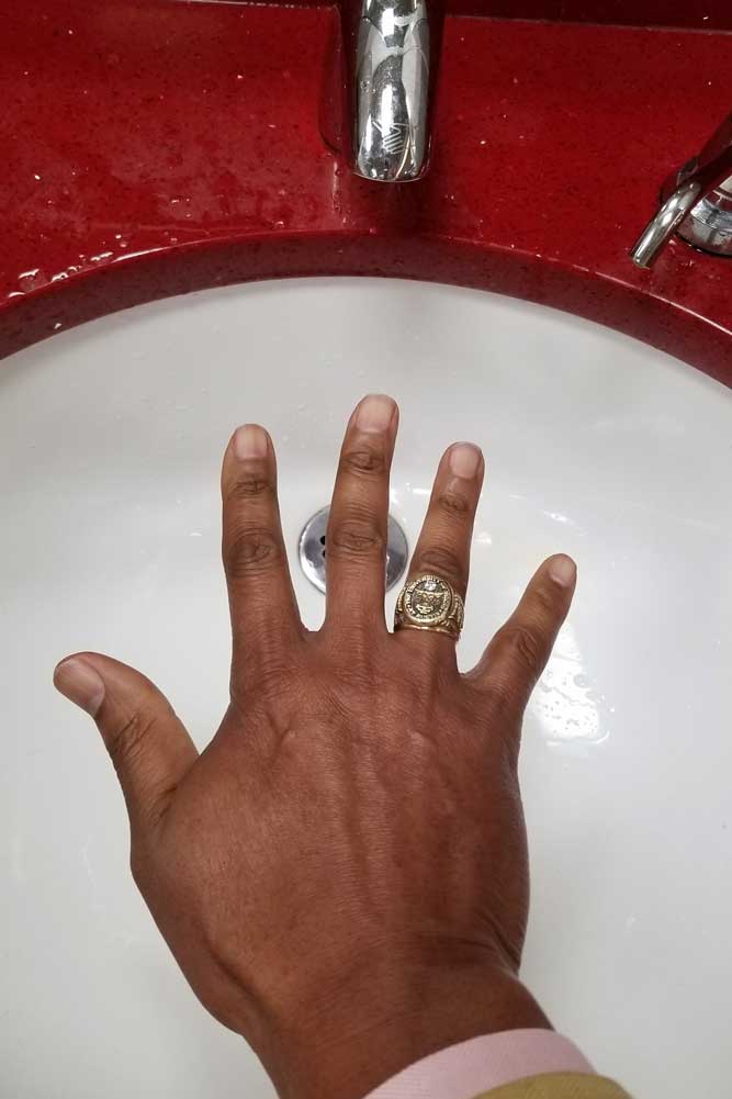 black man holding hand under automatic faucet that isn't turning on