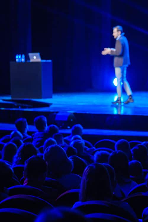 Man walking and talking and gesturing on stage