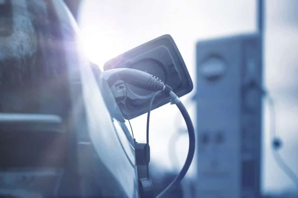photo of plug in electric car with sun in the background