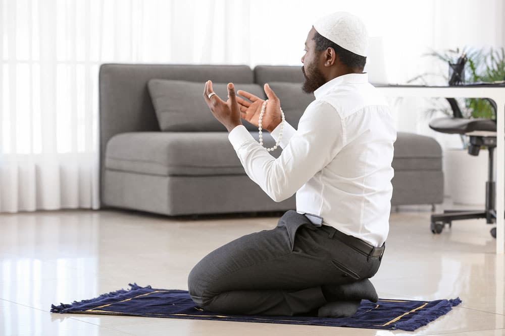 African American Muslim man praying in office