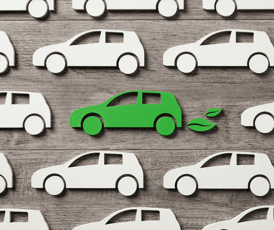 A group of green paper cars on a wooden background, symbolizing the shift towards electric vehicle production as EU countries aim to end ICE vehicles.