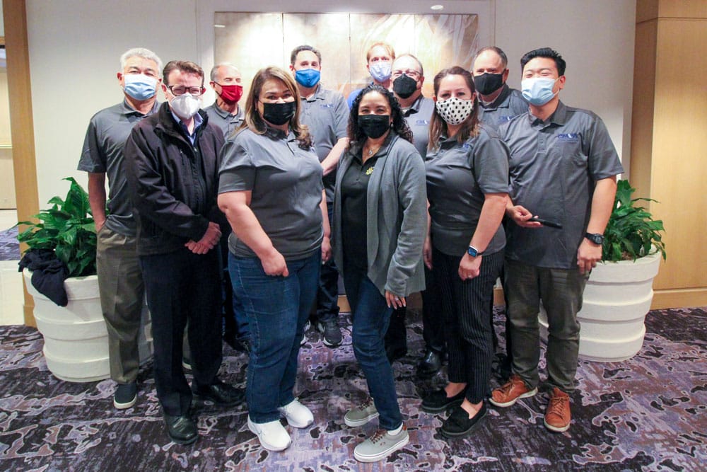 A group of people wearing face masks in a lobby, promoting safety measures in the parking & mobility industry.