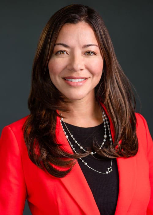 A smiling woman in a red blazer, serving on the IPMI Board.