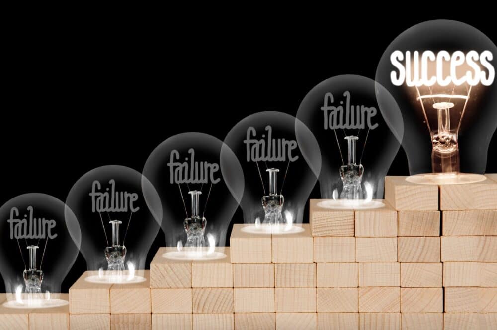 Light bulbs on wooden blocks, representing the duality of success and failure.