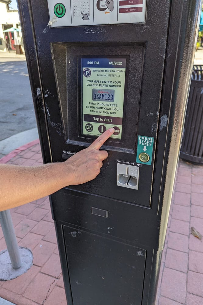 A person is using license plate recognition to collect parking data from a parking meter.