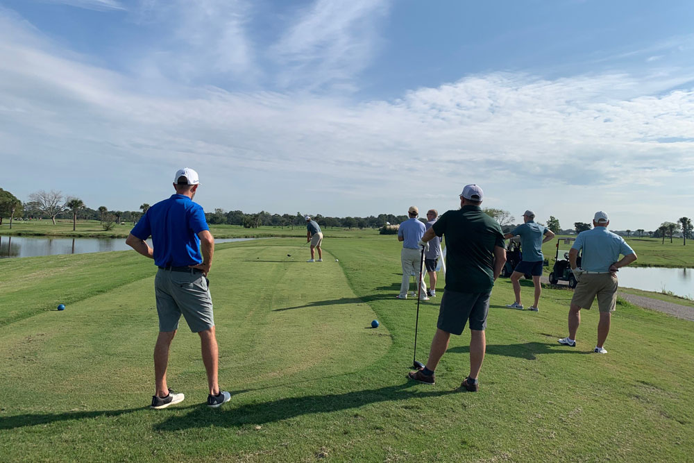 A group of people standing on a golf course during a CPMA event.