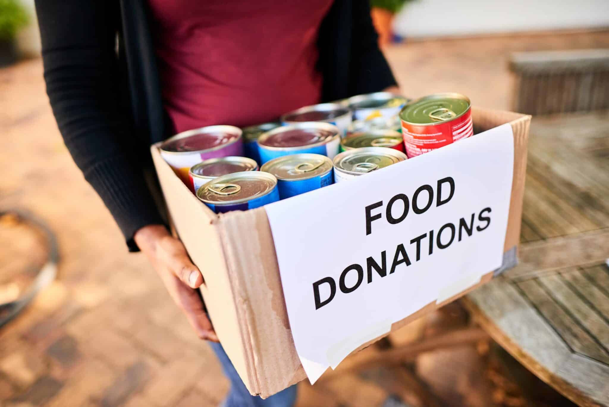 A woman holding a box of food donations.
