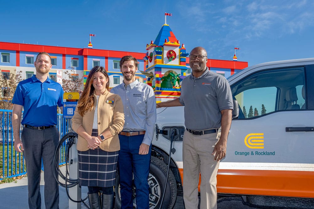 Four people standing in front of an electric vehicle at Legoland New York.