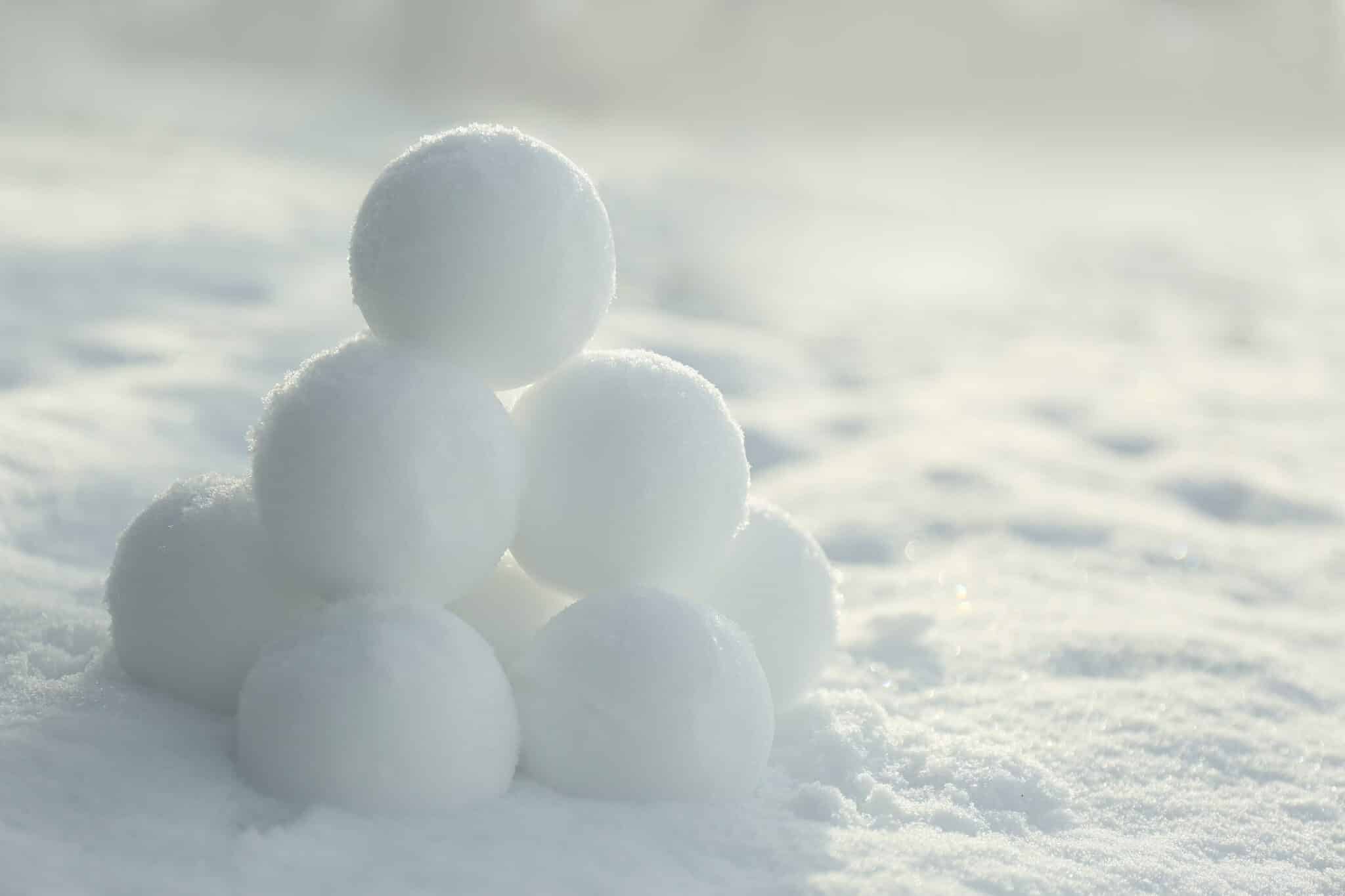 A pile of white snowballs on the ground, ready to be thrown in a lively snowball fight.