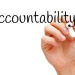 A hand gracefully inscribing the word "accountability" on a pristine white background.