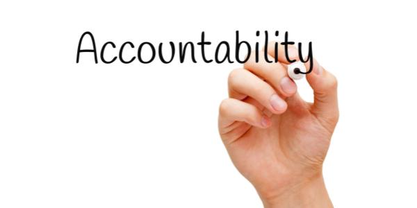 A hand gracefully inscribing the word "accountability" on a pristine white background.