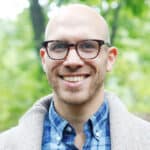 A bald man wearing glasses and a plaid shirt, named Nicholas Klein.
