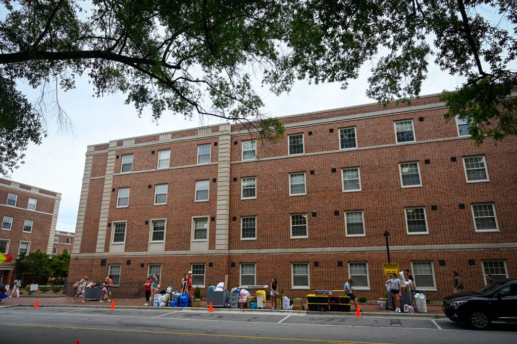 University students standing in front of a brick building during move-in day.