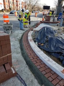Construction workers building curb along the side of the new intersection