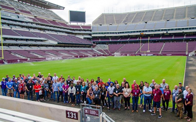Photo of large group in front of the field of an otherwise empty stadium at Texas A&M University