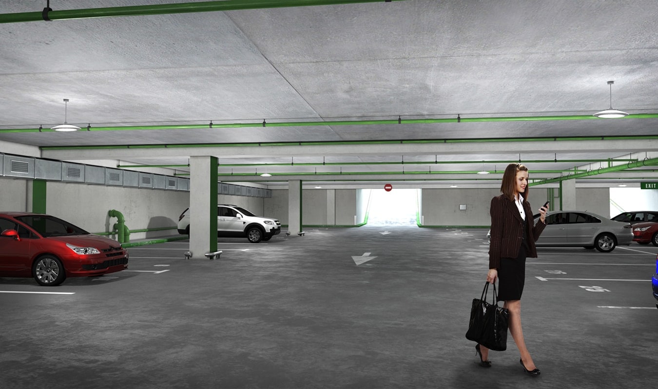A woman is standing next to a car in a well-lit parking garage.