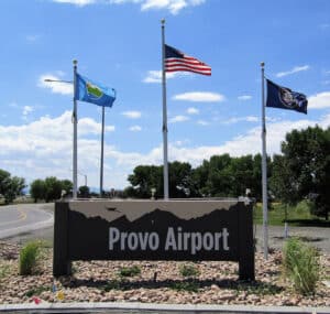 Photo of sign that says "Provo Airport" in front of 3 flags