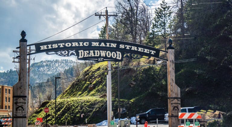 Entrance sign over the road into Deadwood, reading: "Historic Main Street — Deadwood"