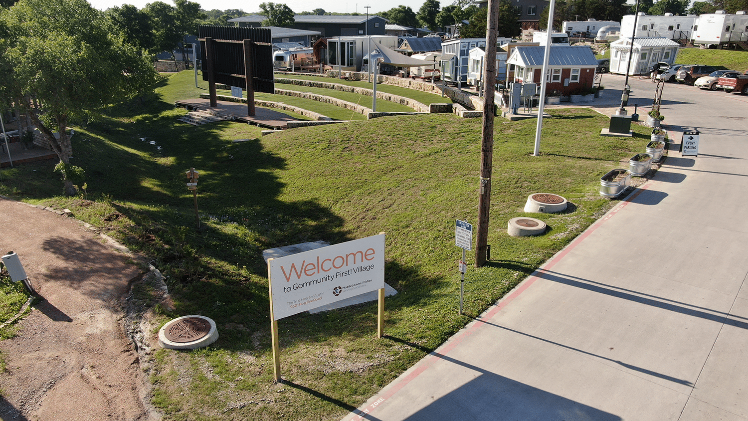 An aerial view of a park with a sign on it indicating transportation services for the homeless.