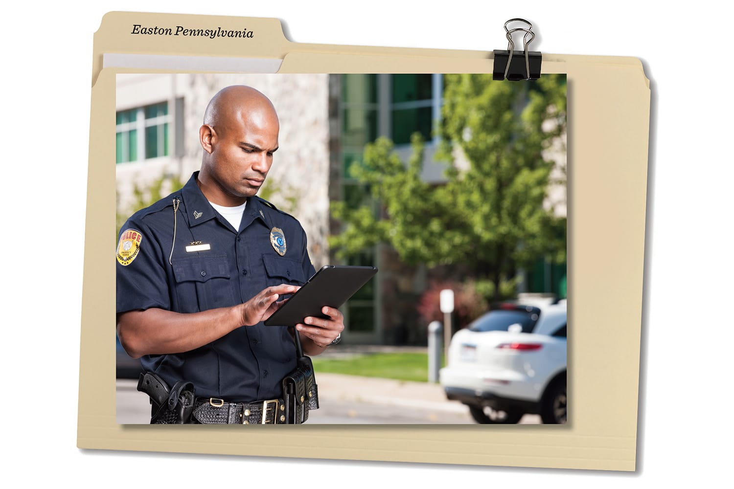 An image of a photo clipped to a file folder. The photo is of an african american male police officer using a tablet.