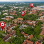 Aerial view of campus with red-brick buildings, greenery, roads, and pins marking EV stations.