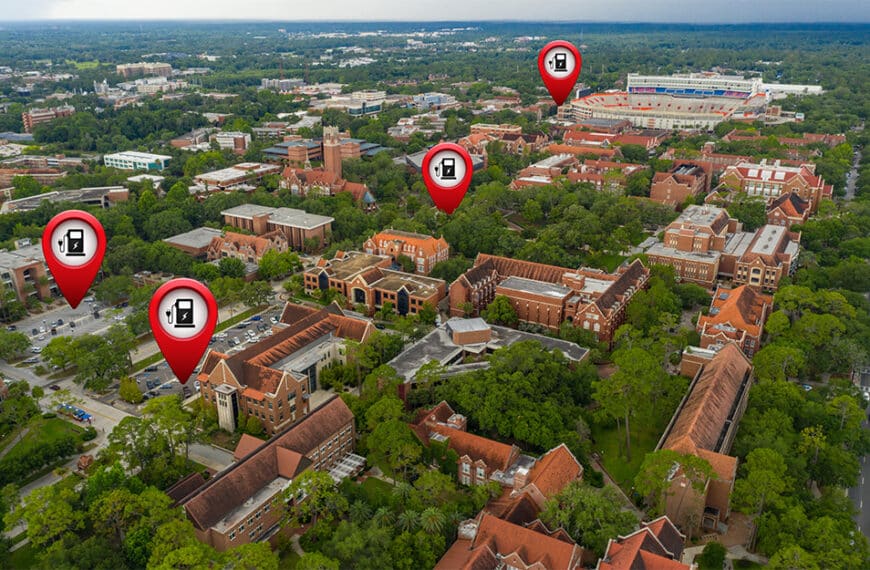 Aerial view of campus with red-brick buildings, greenery, roads, and pins marking EV stations.