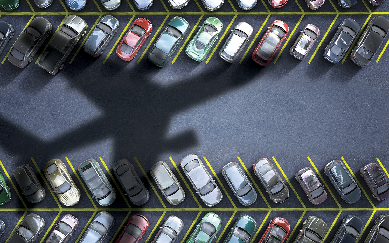 Aerial view of a parking lot with a shadow of an airplane stretching across the asphalt.