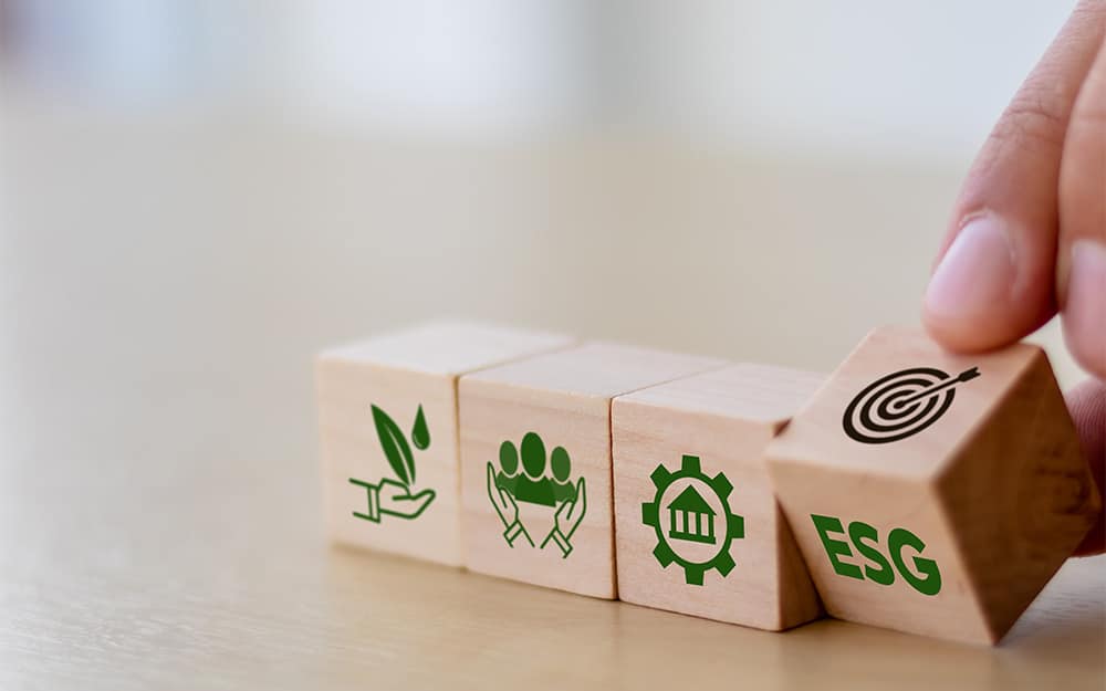 Hand flipping a wooden block in a series with ESG sustainability icons.