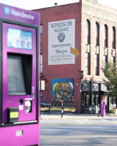 Parking meter in focus with Windsor Square sign and mural in the background.
