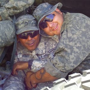 Two soldiers are posing for a photo in a military vehicle.