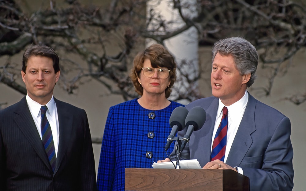 Three people standing at a podium in front of a tree.