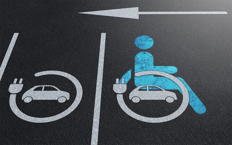 Pavement signage showing an electric vehicle charging station and a wheelchair accessible parking space with directional arrows.