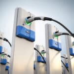 A row of electric vehicle charging stations against a clear sky.